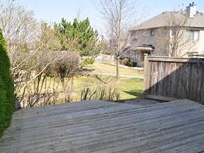 Toronto apartment for rent - A wooden deck overlooks a backyard with a house and trees.