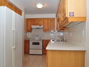 Toronto apartment for rent - A kitchen with wooden cabinets and a white fridge.