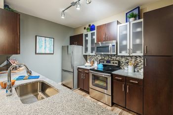 Nona park village apartments pool area gourmet kitchens with tile backsplash, granite countertops, custom cabinetry, and stainless steel appliances