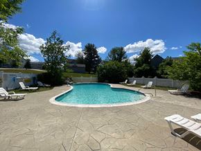 Manchester apartment for rent - A pool surrounded by a stone patio and lawn chairs.