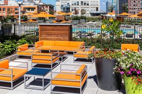 Jersey City apartment for rent - a lounge area on the rooftop of a building with orange couches and tables