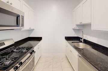 Brighton apartment for rent - a kitchen with white cabinets and a stove and a sink
