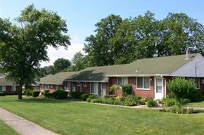 Cincinnati apartment for rent - A row of houses with green lawns and trees in the background.