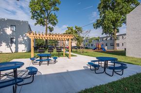 Suitland-Silver Hill apartment for rent - a patio with picnic tables and a wooden pavilion with a playground in the background