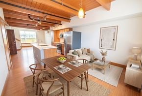 Seattle apartment for rent - Open-concept apartment with wood beam ceiling, dining set, living area, and kitchen island.