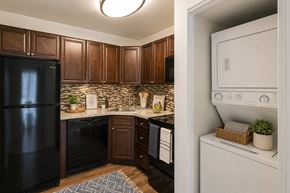 Baltimore apartment for rent - A black refrigerator is in a kitchen with brown cabinets.