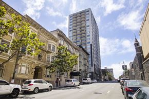 San Francisco apartment for rent - A street view with cars parked on the side and a tall building in the background.