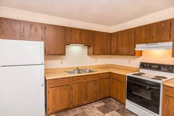 Whitewood apartment for rent - a kitchen with white appliances and wooden cabinets