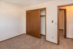 Whitewood apartment for rent - a bedroom with a door to a closet and a carpeted floor