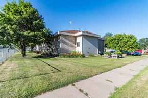 Little Falls apartment for rent - A building with a flag on top is surrounded by a grassy area and a sidewalk.