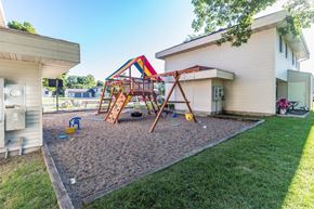 Little Falls apartment for rent - A playground with a slide and swings is in front of a house.