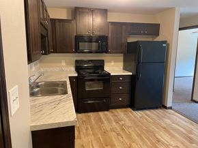 Duluth apartment for rent - a kitchen with black appliances and wooden floors