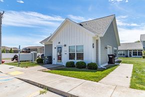 Mandan apartment for rent - the front of a white house with a sidewalk and grass