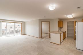 Mandan apartment for rent - an empty living room with a kitchen and a door to a balcony