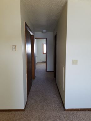 Newell apartment for rent - a hallway of a house with a carpeted floor and white walls and wooden doors