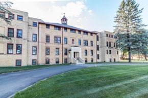 Little Falls apartment for rent - A large building with a clock tower and a tree in front of it.