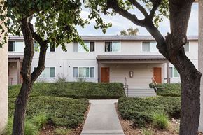 San Diego apartment for rent - a sidewalk in front of a white building with trees and bushes
