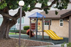 San Diego apartment for rent - a playground with a swing set in front of a building