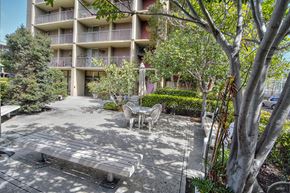 San Diego apartment for rent - a bench and chairs in a courtyard in front of an apartment building