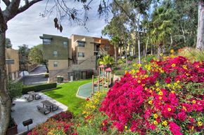 San Diego apartment for rent - a park with flowers and benches in front of an apartment building
