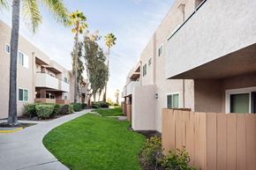 Spring Valley apartment for rent - a street view of a building with green grass and palm trees