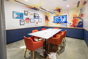 Allston apartment for rent - a conference room with a white table and orange chairs and a tv on the wall