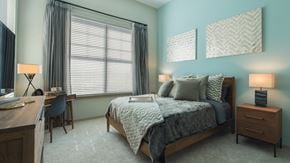 Nashville apartment for rent - A bedroom with a large bed, a desk, and a chair.