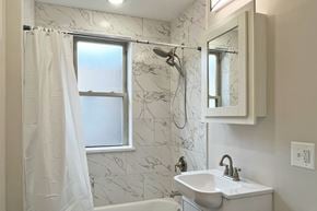 Oak Park apartment for rent - A bathroom with a marble wallpaper and a white sink.