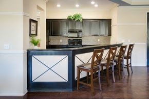 Santa Ana apartment for rent - A kitchen island with a black and white design sits in front of a counter with four chairs.