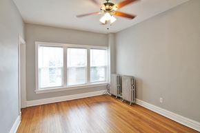 Chicago apartment for rent - an empty living room with a ceiling fan and three windows