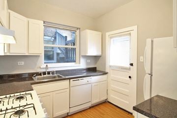 Chicago apartment for rent - a kitchen with white cabinets and a sink and a refrigerator