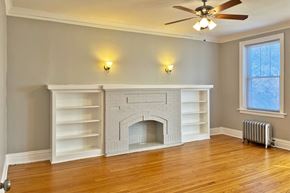 Oak Park apartment for rent - A white fireplace with a mantle and shelves is in a room with wood floors and a ceiling fan.