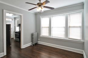 Chicago apartment for rent - an empty living room with a ceiling fan and three windows
