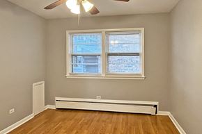 Oak Park apartment for rent - A room with a window, a ceiling fan, and a radiator on the floor.