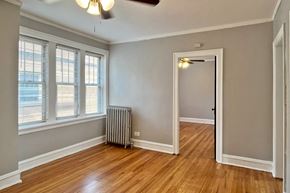 Oak Park apartment for rent - A room with a wooden floor, a ceiling fan, and a window with blinds.