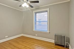 Oak Park apartment for rent - A room with a ceiling fan, a window with blinds, and a radiator on the wall.