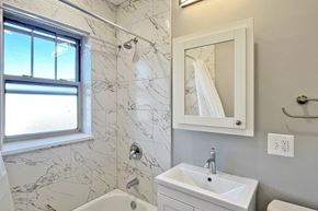 Oak Park apartment for rent - A white bathroom with a marble tile shower and a window.
