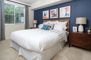 Costa Mesa apartment for rent - A bedroom with a white bed and a wooden nightstand.