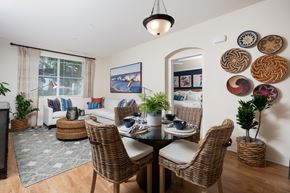 Costa Mesa apartment for rent - A dining room with a table set for four and a couch with a pillow.
