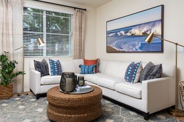 Costa Mesa apartment for rent - A living room with a white couch, a wicker coffee table, and a large painting on the wall.