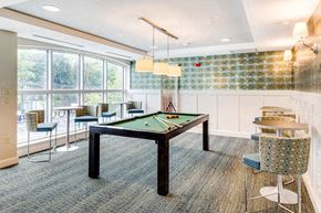 Newton apartment for rent - a billiards table in a game room with seating and a large window