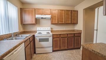 Broken Arrow townhouse for rent - an empty kitchen with wooden cabinets and a white stove and oven