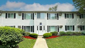 Farmington Hills apartment for rent - A building with a white door and windows with bushes in front.