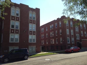 Chicago apartment for rent - a large red brick building with two cars parked in front of it