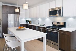 Ossining apartment for rent - a kitchen with stainless steel appliances and a white table