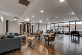 Calgary apartment for rent - A living room with a grey couch, wooden floor, and a large window.