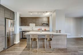 Calgary apartment for rent - A modern kitchen with a bar stool and a fridge.