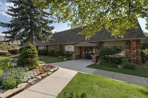 Lansing apartment for rent - the front of a brick house with a sidewalk and trees