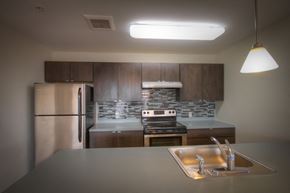 Somerset apartment for rent - kitchen with stainless steel appliances, dark wood cabinets, grey patterned tile back splash, and grey counter tops
