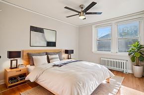 Denver apartment for rent - A bedroom with a large bed, a ceiling fan, and a potted plant.